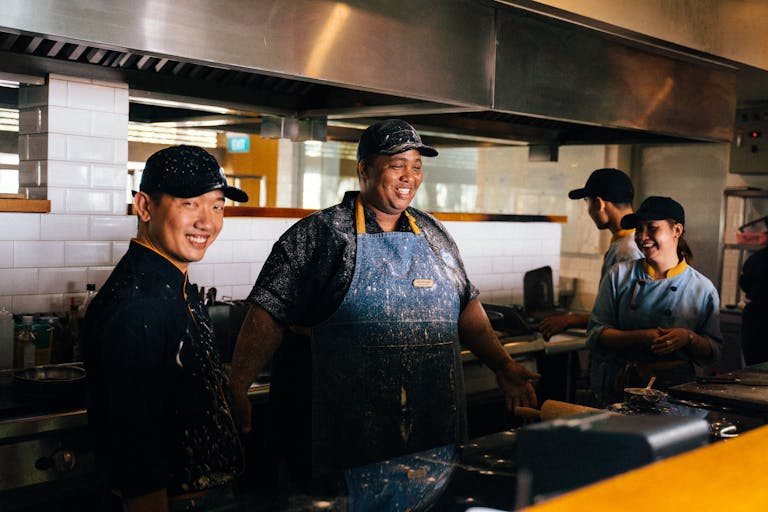 Chefs enjoying their work in a busy restaurant kitchen, highlighting teamwork and culinary passion.